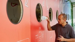 Man deponeert een plastic fles in een grote kleurrijke recyclewand.
